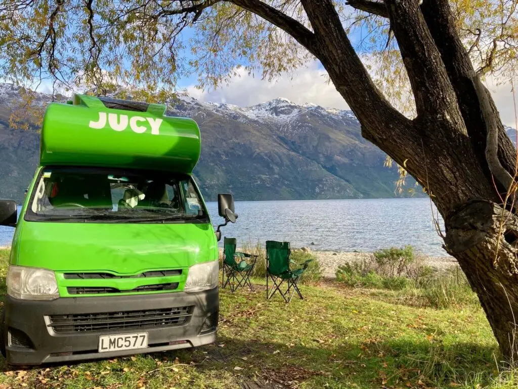 Un van Jucy Condo vert flash sur le bord de l'eau en Nouvelle-Zélande