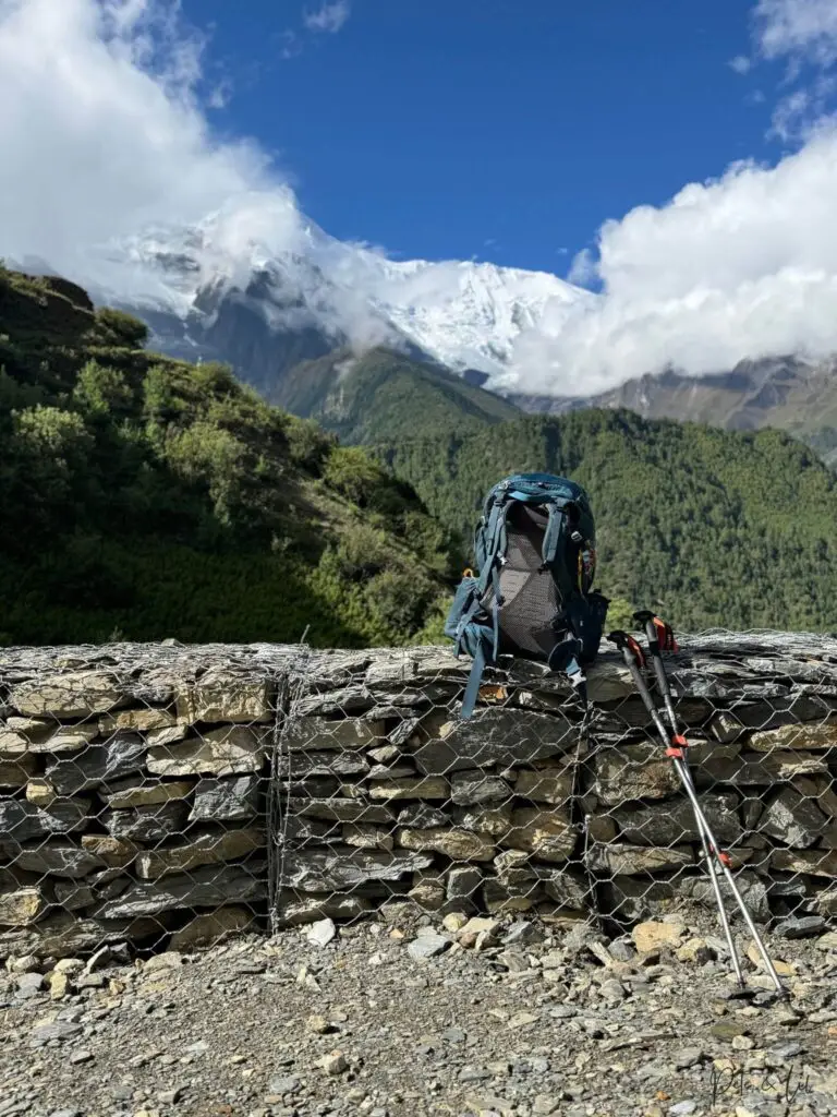 Sac à dos de voyage et bâtons de marche face aux montagnes enneigées du Népal