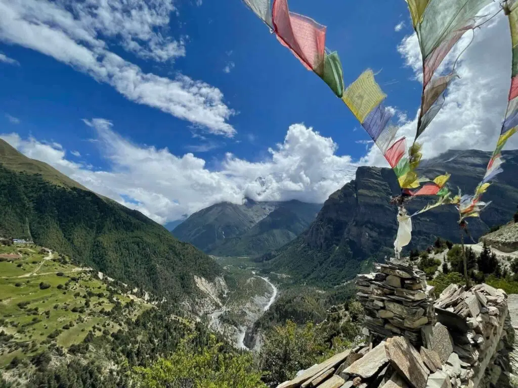 Vallée avec sommet enneigé dans les nuages et drapeaux de prières