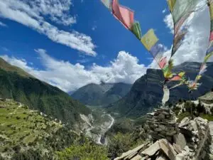 Vallée avec sommet enneigé dans les nuages et drapeaux de prières