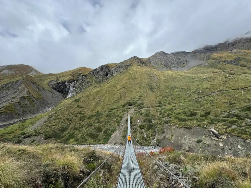 Un randonneur sur un pont suspendu vide avec vue sur les montagnes