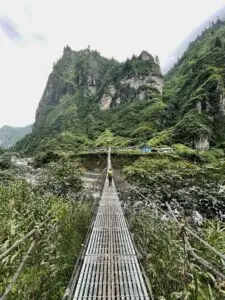 Pont suspendu avec randonneur et montagnes en arrière-plan
