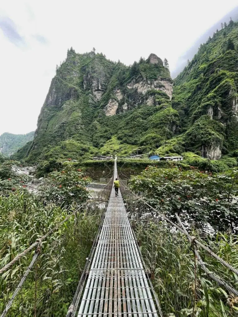 Pont suspendu avec randonneur et montagnes en arrière-plan