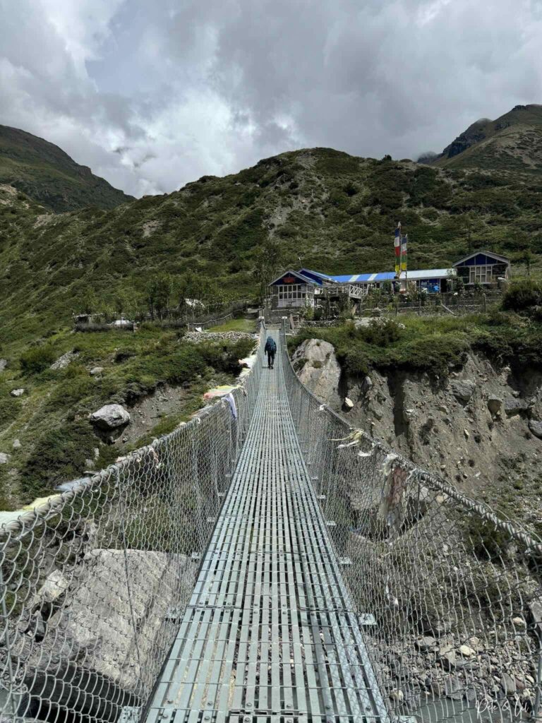 Randonneur traversant un pont devant un guesthouse