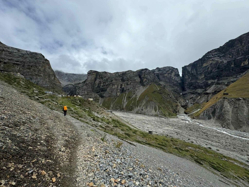Randonneur dans la vallée rocheuse avec Thorung Phedi en arrière-plan