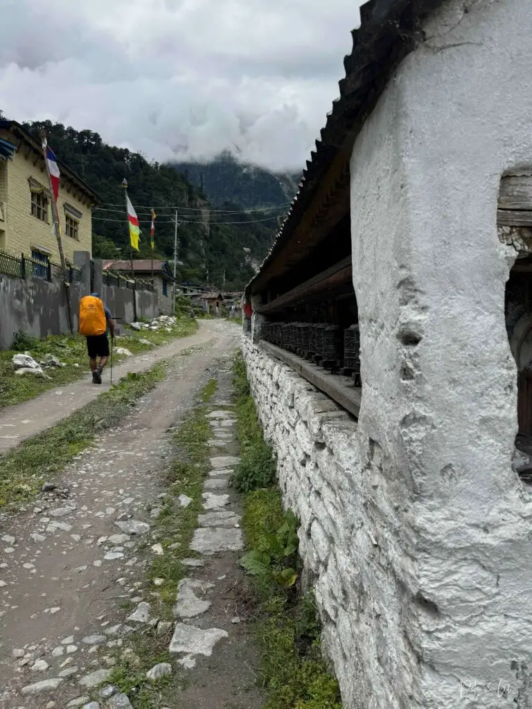 Randonneur sur la route avec mur de moulins à prières