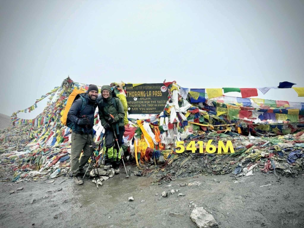 Couple de randonneurs au sommet du col de Thorung La avec drapeaux de prières