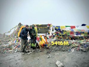 Couple de randonneurs au sommet du col de Thorung La avec drapeaux de prières