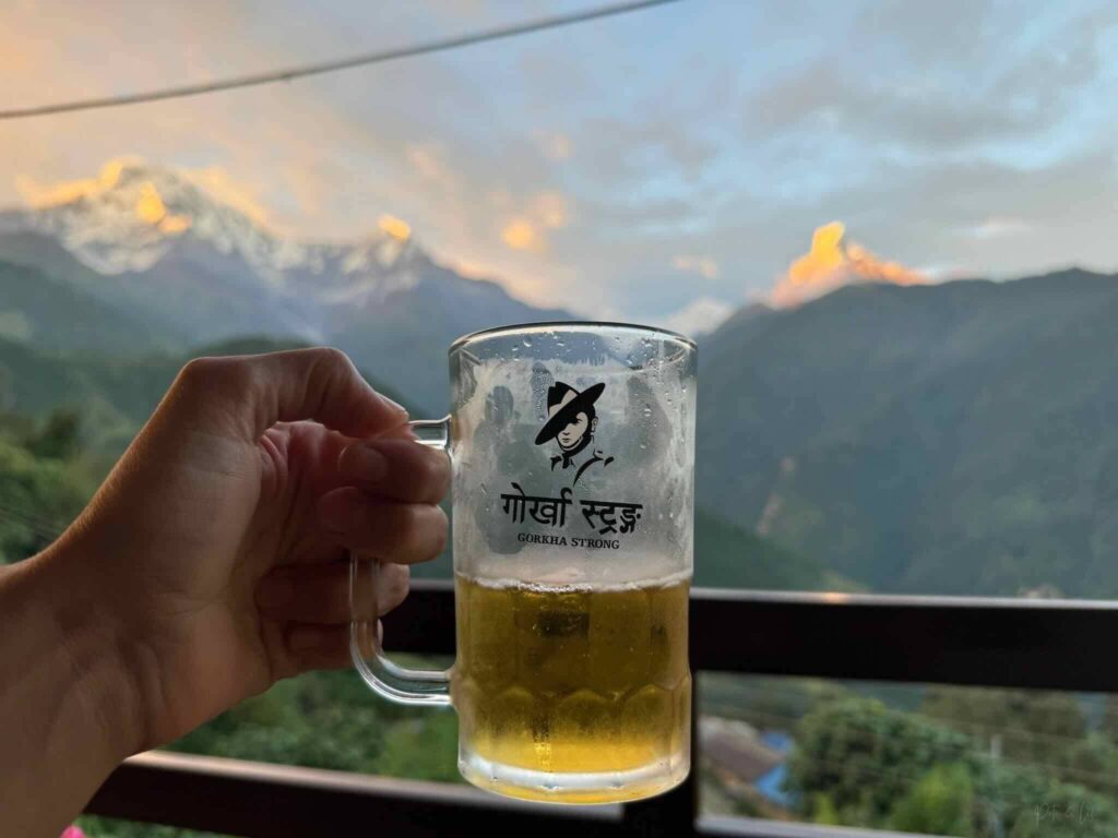 Bière au premier plan avec sommets enneigés pour célébrer la fin du trek