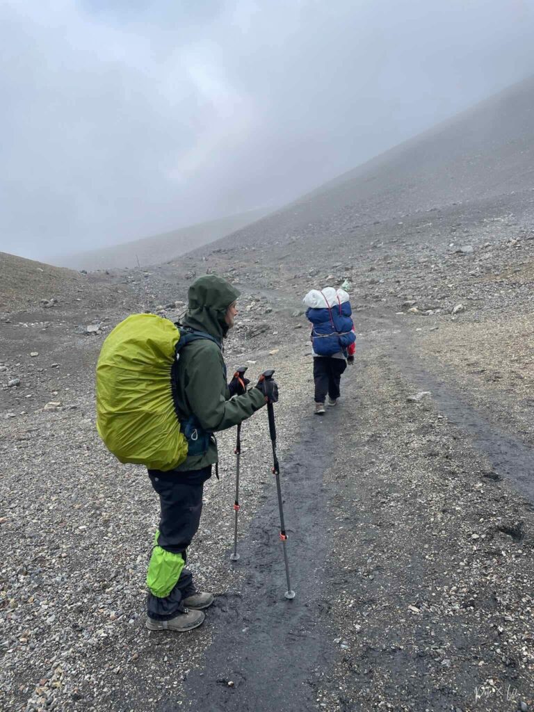 Randonneuse avec sac à dos et porteur népalais avec charges importantes